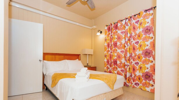 A hotel room with a bed, a nightstand, a lamp, and a shower curtain with a floral pattern. - Martin's Way@Potters Village 2 BR Apartment (Potters Village)