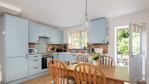 A modern kitchen with light blue cabinets, a wooden dining table, and chairs.