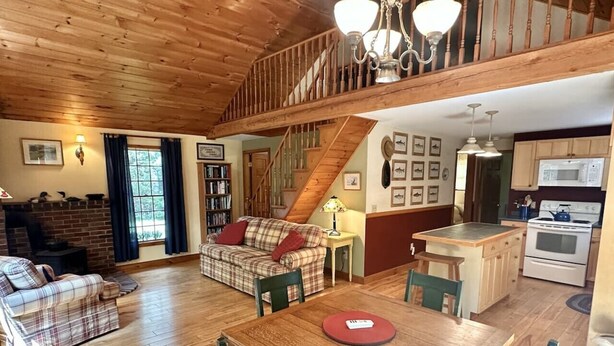 Un intérieur chaleureux avec une table à manger en bois, un canapé et un escalier menant à un niveau supérieur.