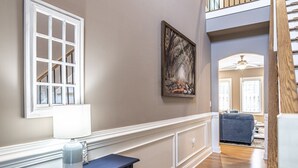 A hallway with a white-framed window, a painting, and a staircase. - Mulligan Manor- 0.2 mile walk to Vitos Ristorante and Pizzeria and many others! (Southern Pines)