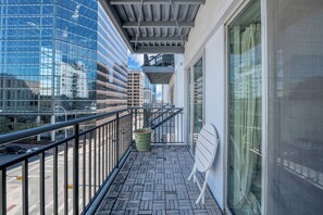 Enjoy the city view from this balcony with a tiled floor and metal railing, featuring a planter.