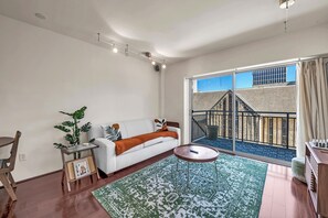 Relax in this stylish living room with a sofa, side table, and rug, and step out to a balcony with a city view.