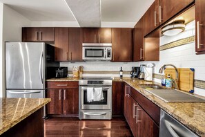 Fully equipped kitchen with stainless steel appliances, dark cabinetry, and granite countertop.