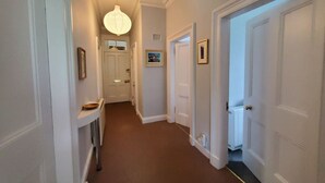 A hallway with white doors, a hanging light fixture, and a radiator. - Little Bay View in Oban (Oban)