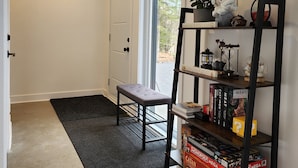 Un couloir propre et moderne, avec un banc, une bibliothèque contenant des jeux de société et une grande fenêtre.