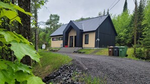 Un bâtiment moderne doté d’un toit en pente, d’une entrée principale et d’une allée gravillonnée qui y m ène.
