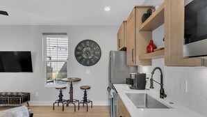 A modern kitchen with a built-in refrigerator, wooden cabinets, and a large wall clock. - Roof Deck|Pet Friendly|E.Nash (Nashville)