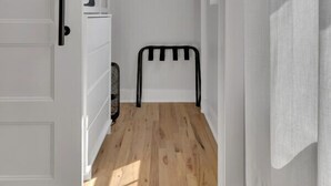 A narrow hallway with a sliding door leading to a closet with shelves and storage bins. - Roof Deck|Pet Friendly|E.Nash (Nashville)