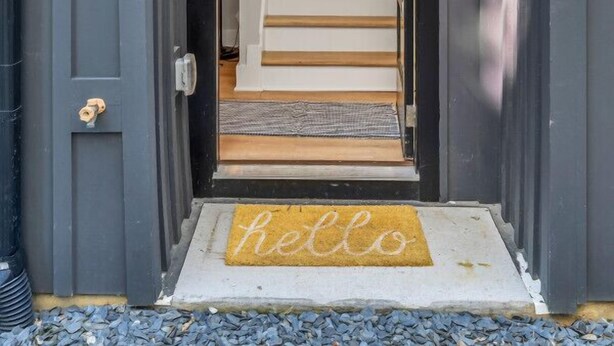 A dark grey door with a "No. 4" sign, a wooden staircase leading inside, and a "hello" mat at the entrance. - Roof Deck|Pet Friendly|E.Nash (Nashville)