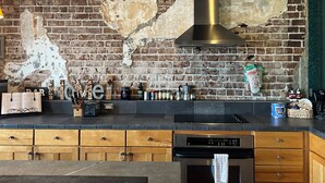 Una cocina con paredes de ladrillo visto, armarios de madera y una campana extractora de acero inoxidable.