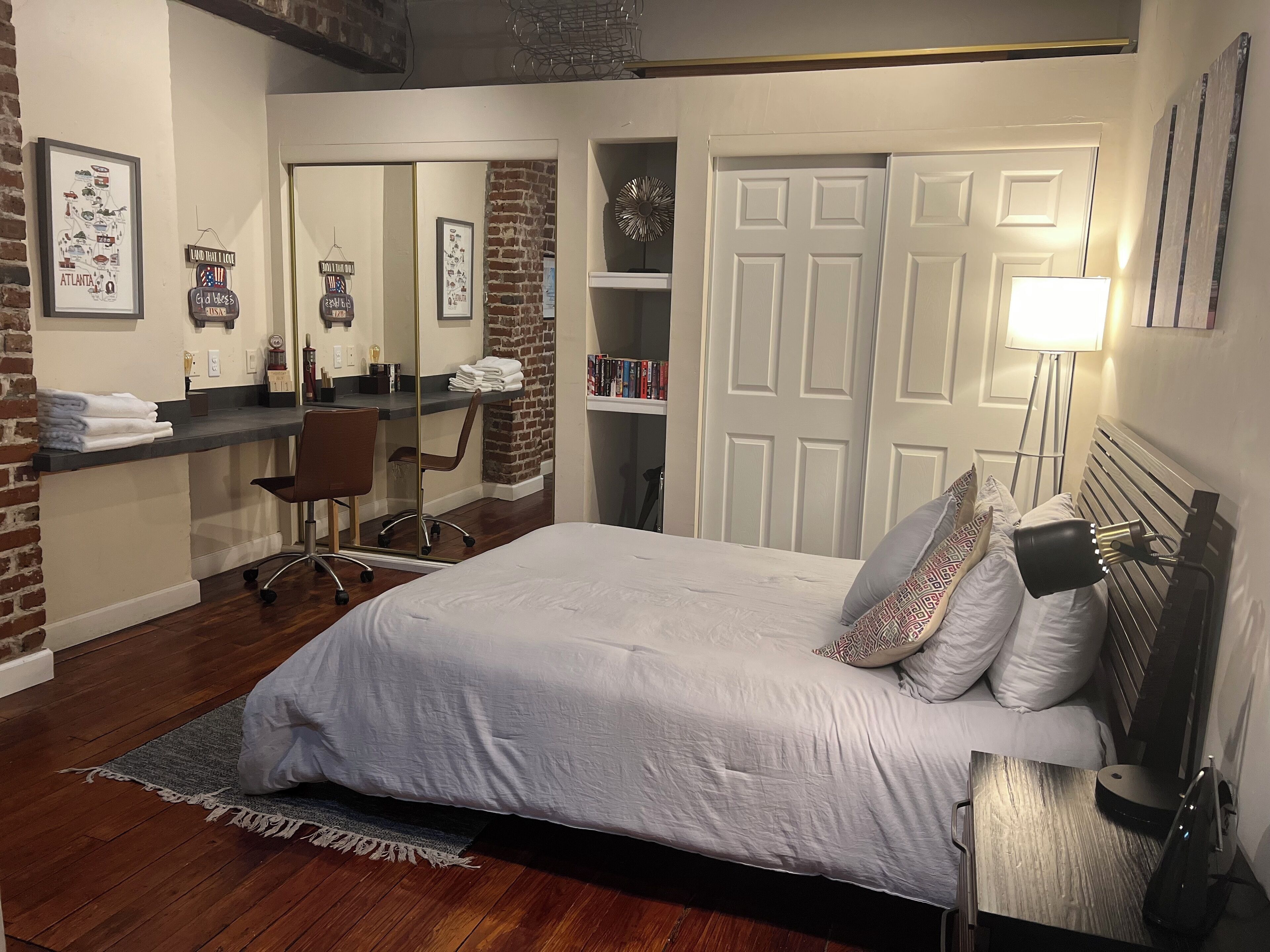 Un dormitorio con cama, escritorio, silla, espejo y armario.