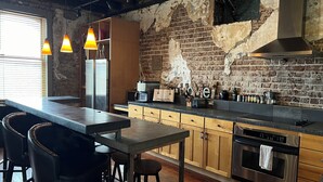 Una cocina moderna con paredes de ladrillo visto, una isla grande con taburetes de bar y electrodomésticos de acero inoxidable.