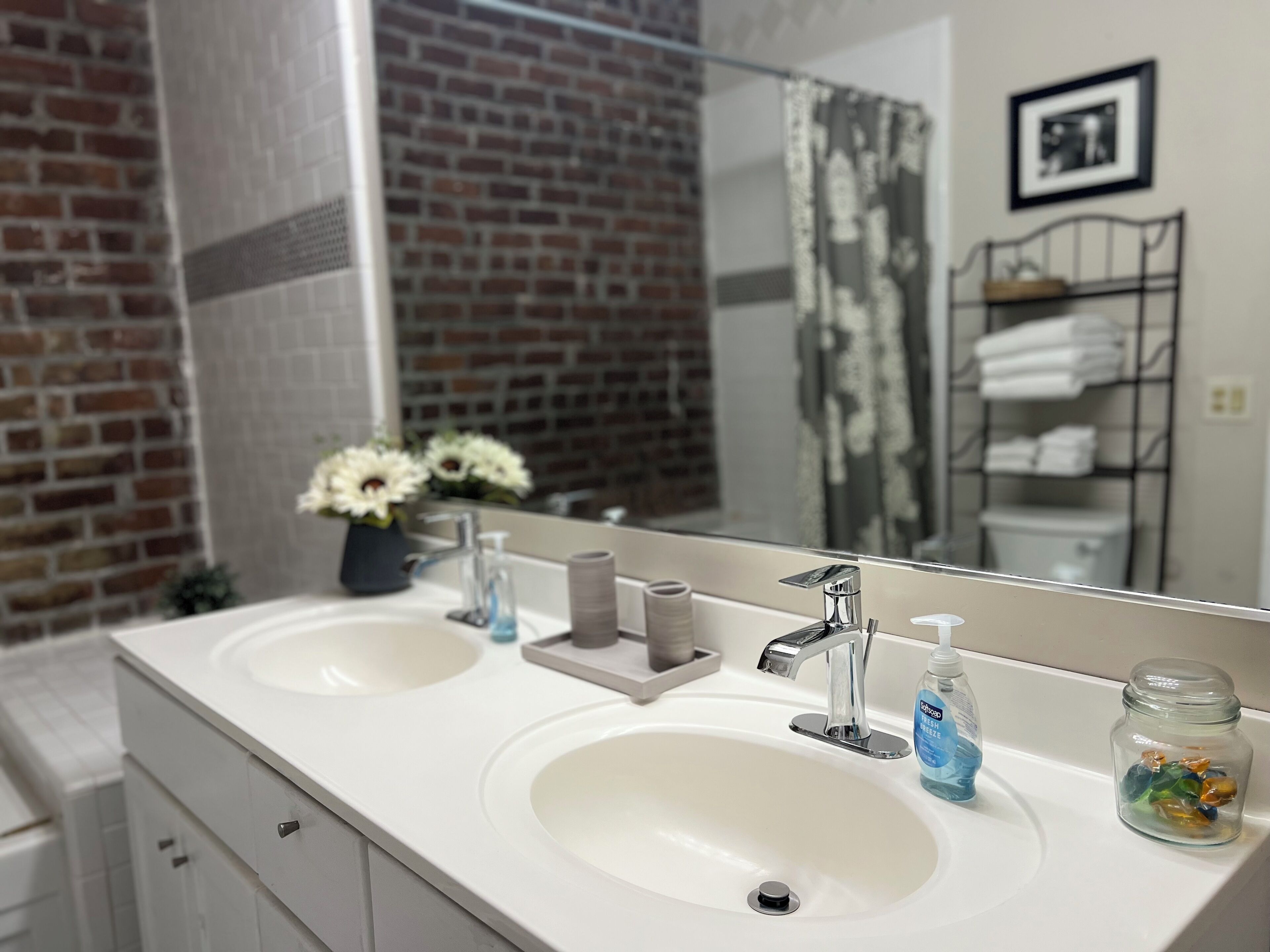 A bathroom with two sinks, a mirror, and a brick wall.