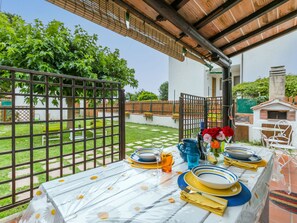 Enjoy a romantic meal under the pergola, surrounded by a beautiful garden and a charming white building.