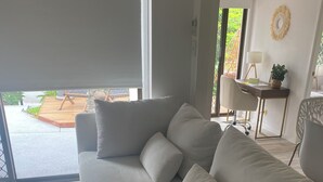 A modern living room with a large sofa, a coffee table, and a view of the outdoors. - Welcome to our serenity in the Gold Coast which is "Bee Cottage".
 (Robina)