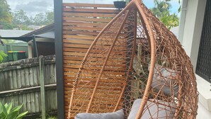 A wicker hanging chair with cushions on a wooden deck. - Welcome to our serenity in the Gold Coast which is "Bee Cottage".
 (Robina)
