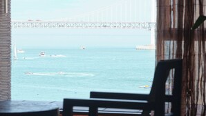 Ένα δωμάτιο με ένα μεγάλο παράθυρο που προσφέρει θέα σε μια γέφυρα και στη θάλασσα.