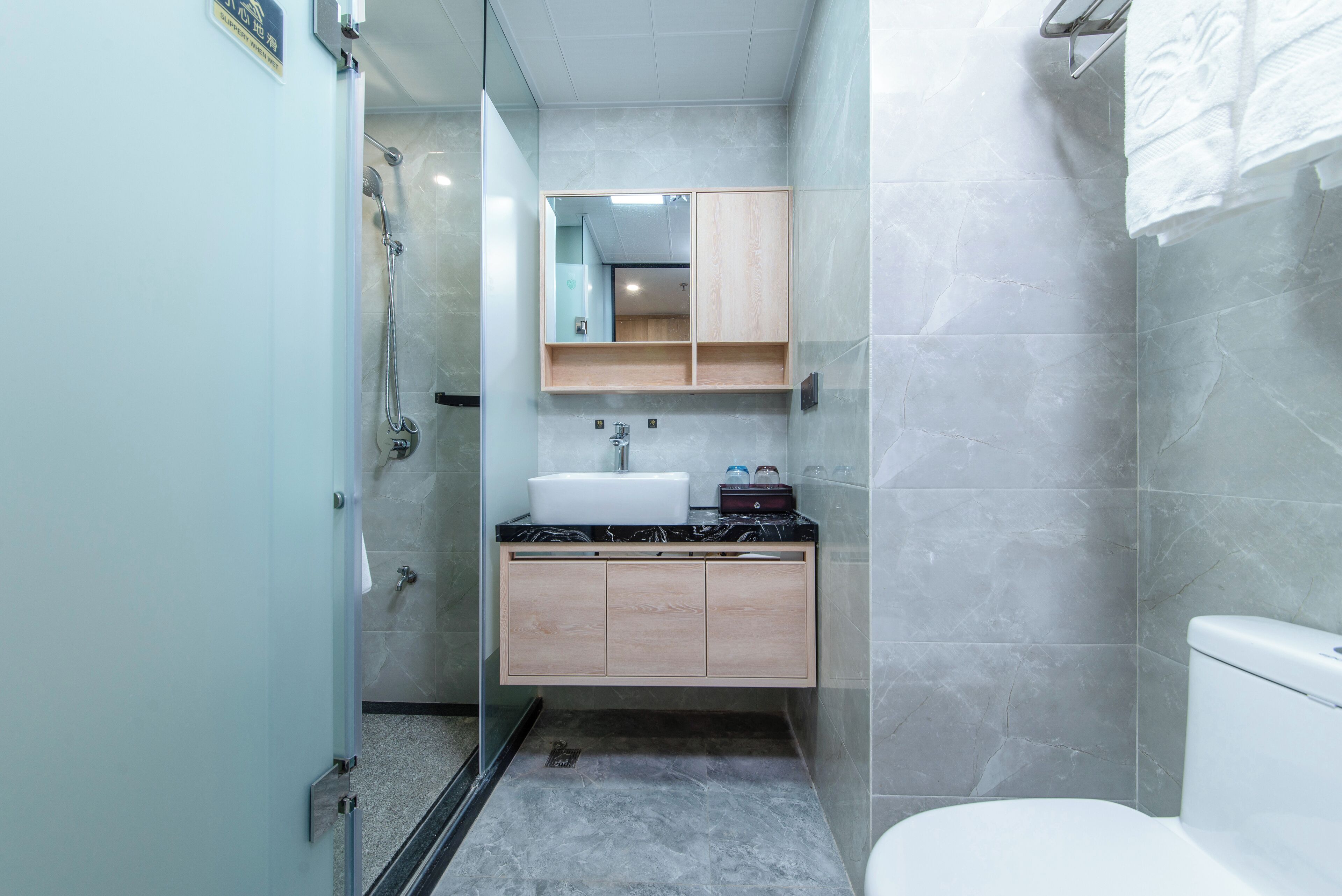 Un baño moderno con cabina de ducha de vidrio, lavamanos blanco y tocador de madera.