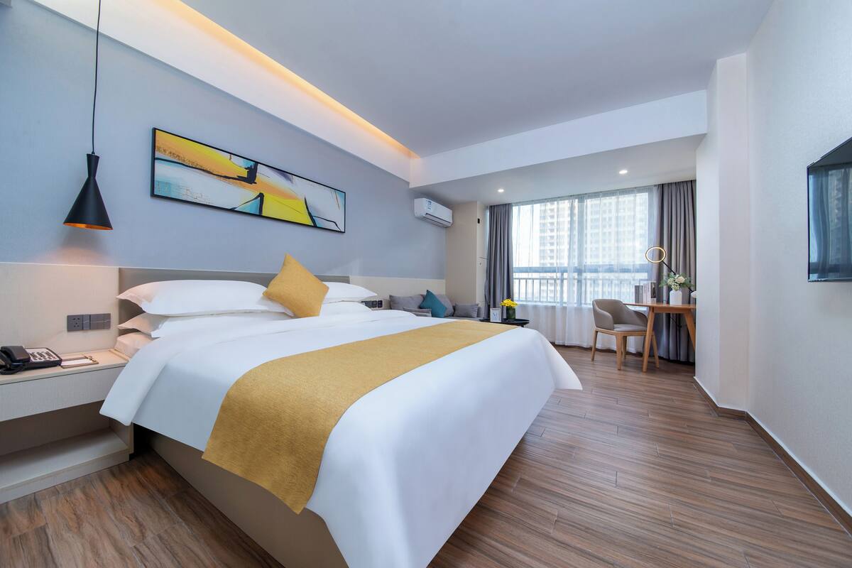 Ein modernes Hotelzimmer mit einem großen Bett, einem Nachttisch und einem Schreibtisch mit Stuhl.