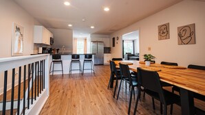 Une cuisine moderne avec un plancher en bois, des meubles blancs et des chaises noires.