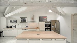Een moderne keuken met witte kasten, een houten kookeiland en roestvrijstalen apparatuur.