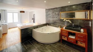 Een moderne badkamer met een vrijstaand ligbad, een houten wastafelmeubel met een wastafel en een grote spiegel.