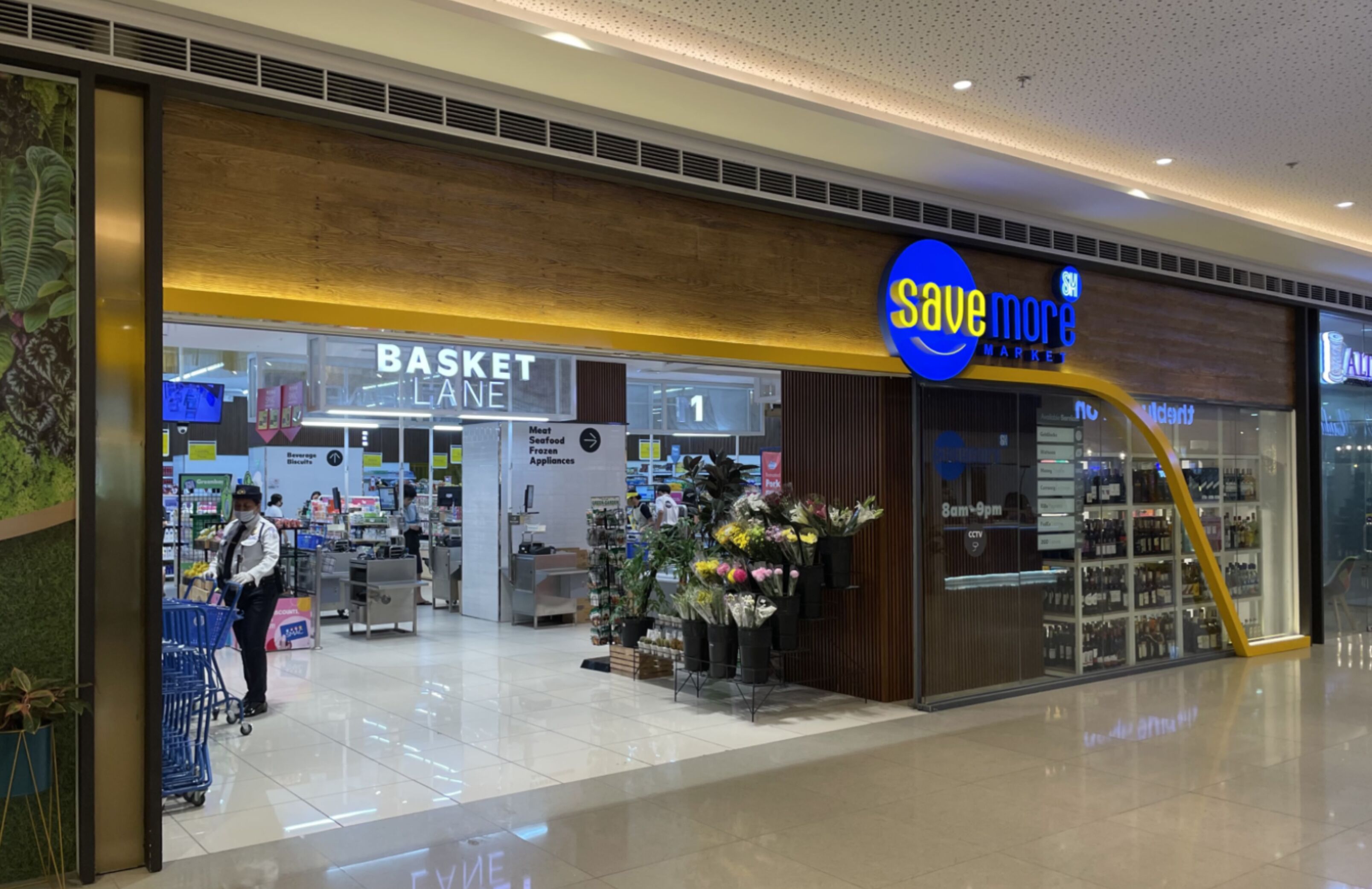 Um centro comercial com uma loja 'Save More Market' e uma loja 'Basket Lane'.