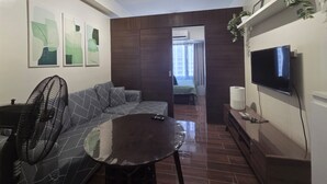 Una sala de estar moderna con sofá, mesa de centro, televisor y ventilador.