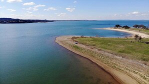 A coastal landscape with a sandy beach and a calm sea. - The GlampBox. Lakefront, 20acres, Starlink Wifi! (Burnet)