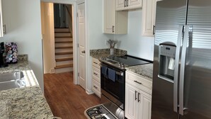 Una cocina moderna con armarios blancos, un refrigerador de acero inoxidable, un horno empotrado y una cafetera.