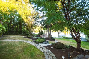 A landscaped garden with a stone pathway, a small pond, and a variety of trees and shrubs.