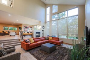 A spacious living room with a large sectional sofa, a fireplace, and large windows providing natural light.