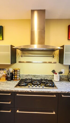 Una cocina moderna con una campana de acero inoxidable, una estufa a gas y muebles oscuros.