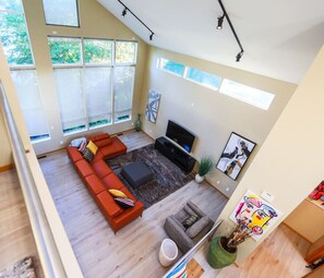 A modern living room with a sectional sofa, a flat-screen TV, and artwork on the walls.