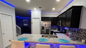 A modern kitchen with a central island, bar stools, and a built-in refrigerator. - Cozy 3-bedroom townhome inHomestead , near Keys, with AC, full kitchen , WiFi (Homestead)