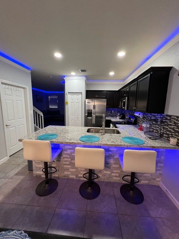 Una cocina moderna con una isla central, taburetes de bar y un refrigerador integrado.