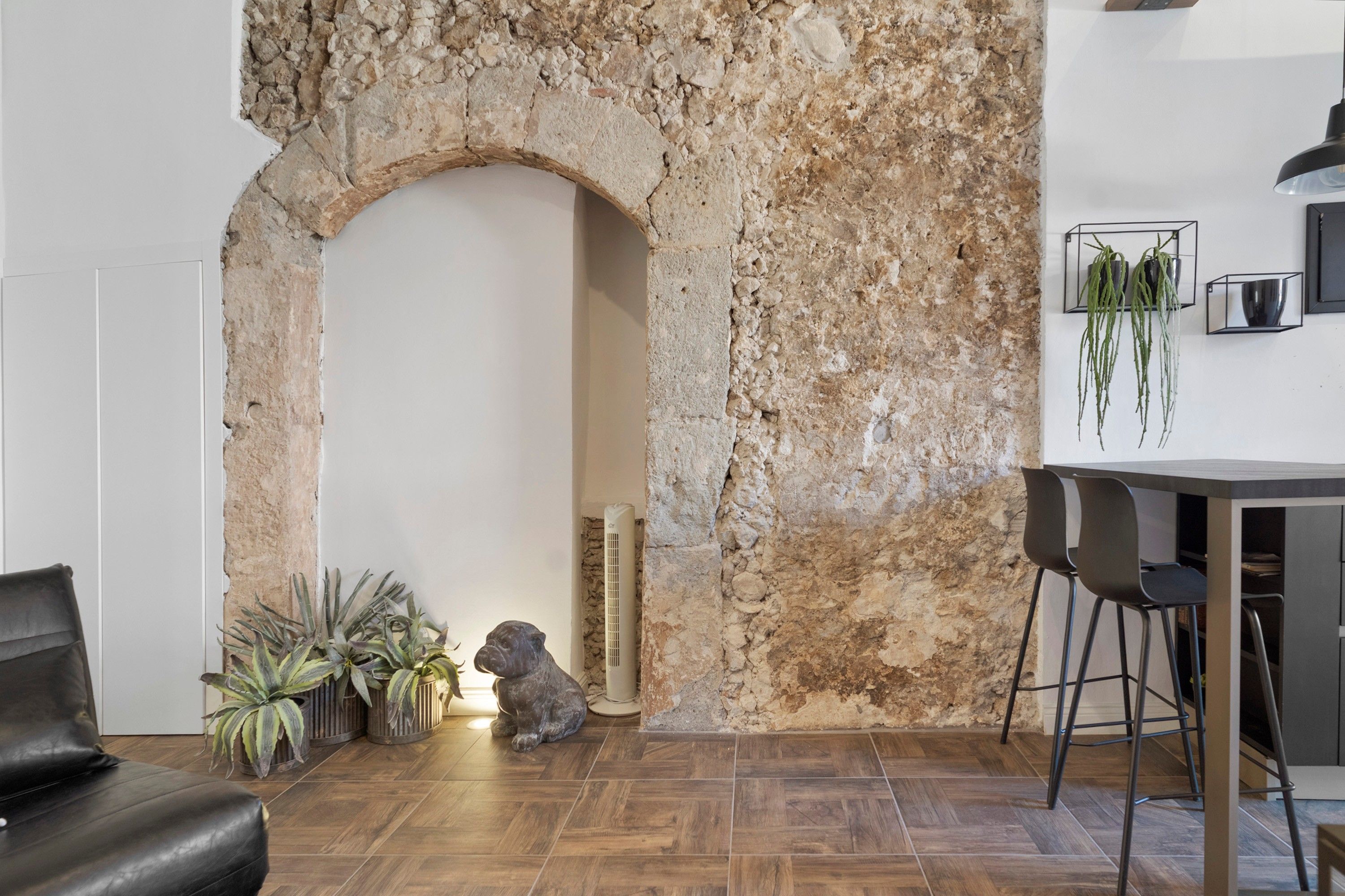 Une pièce avec un mur en pierre, un canapé, une table à manger avec des chaises et des plantes en pot.