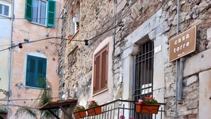 A cobblestone street with a building featuring a stone facade, a metal balcony with flower pots, and a sign reading 'casa torre.' - Apartment 'Appartamento Luxury - Torre' with Air Conditioning (Terracina)