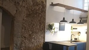 A modern kitchen with a stone wall, a dining area with chairs, and pendant lighting. - Apartment 'Appartamento Luxury - Torre' with Air Conditioning (Terracina)