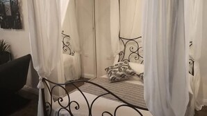 A four-poster canopy bed with a metal frame, white curtains, and a patterned pillow. - Apartment 'Appartamento Luxury - Torre' with Air Conditioning (Terracina)