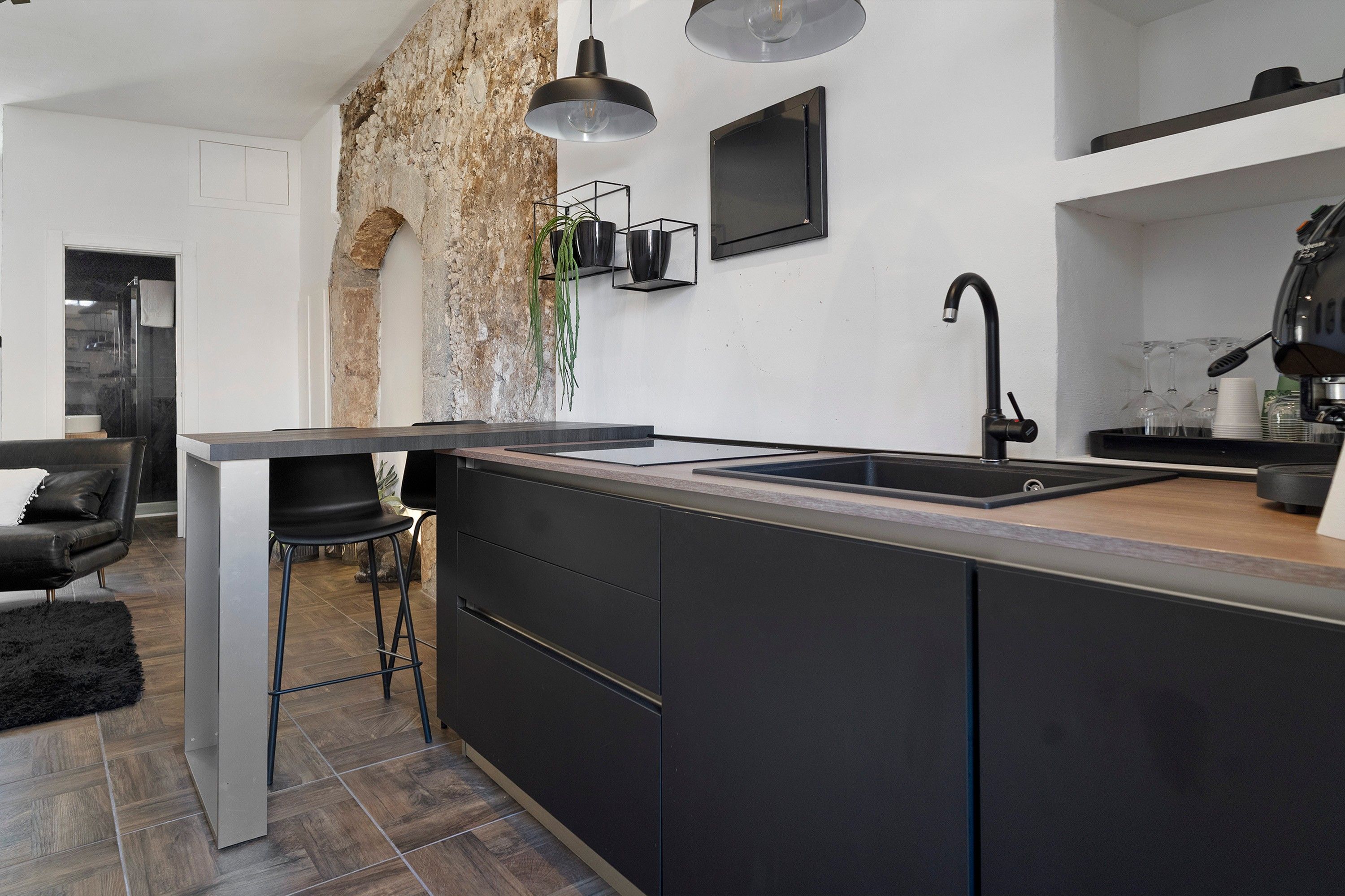 A modern kitchen with a central island, black cabinetry, a built-in sink, and pendant lighting.