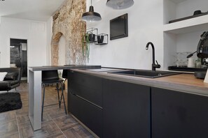 A modern kitchen with a central island, black cabinetry, a built-in sink, and pendant lighting. - Apartment 'Appartamento Luxury - Torre' with Air Conditioning (Terracina)