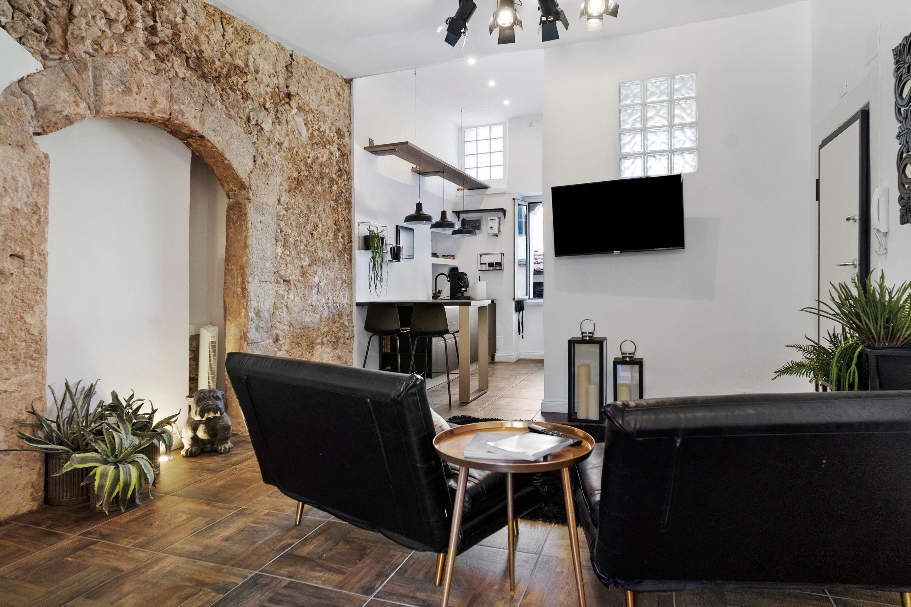 Un salon moderne avec des canapés en cuir noir, une table basse et un mur en pierre.