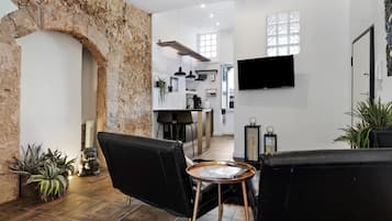 Un salon moderne avec des canapés en cuir noir, une table basse et un mur en pierre.