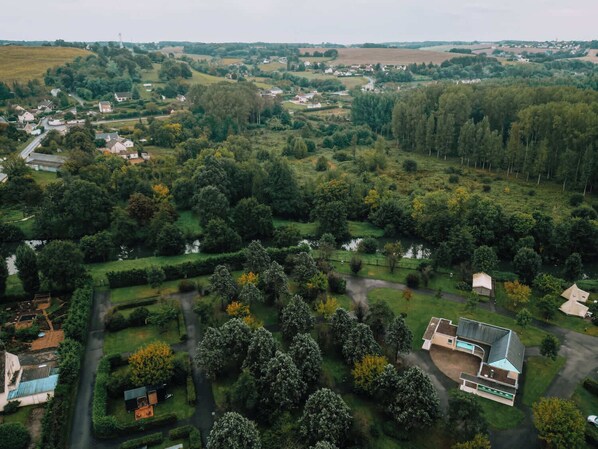 An aerial view of a residential area with houses, green spaces, and a river.