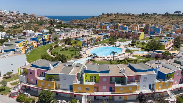 A coastal residential area with colorful buildings, a central swimming pool, and a view of the sea. - Romantic flat with Jacuzzi &Pool (Albufeira)