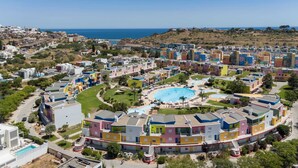 A coastal resort with colorful buildings, a central swimming pool, and a view of the sea. - Romantic flat with Jacuzzi &Pool (Albufeira)