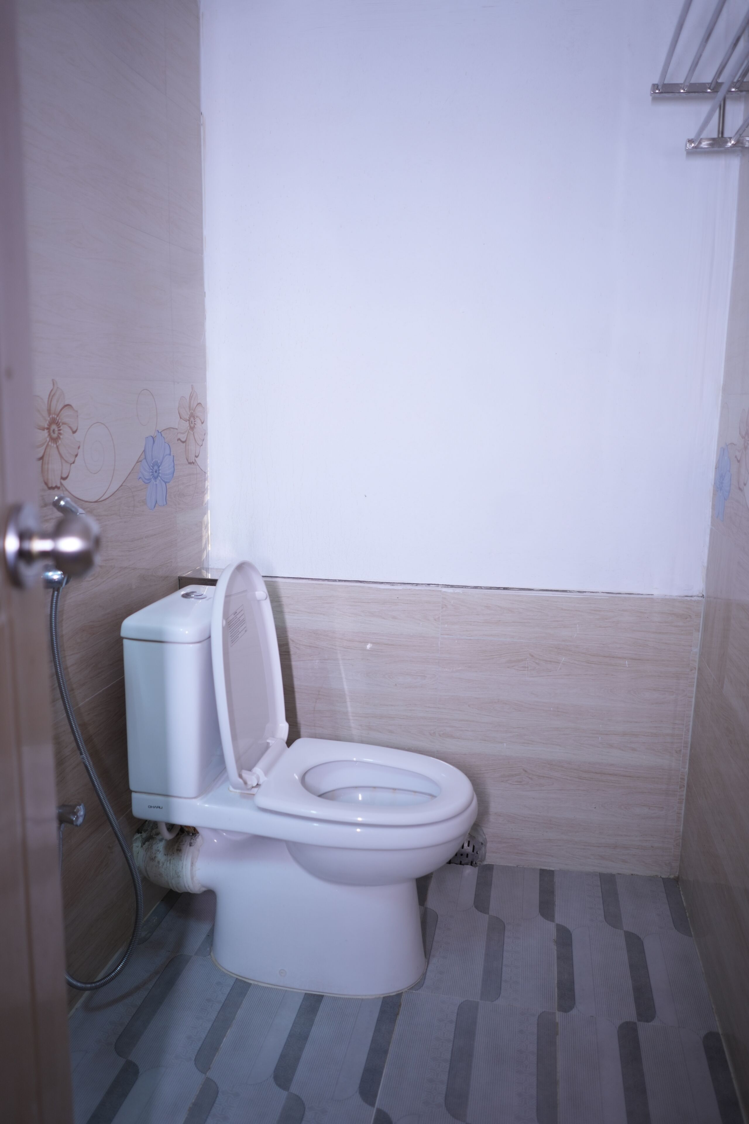 A bathroom with a toilet, shower, and tiled floor.