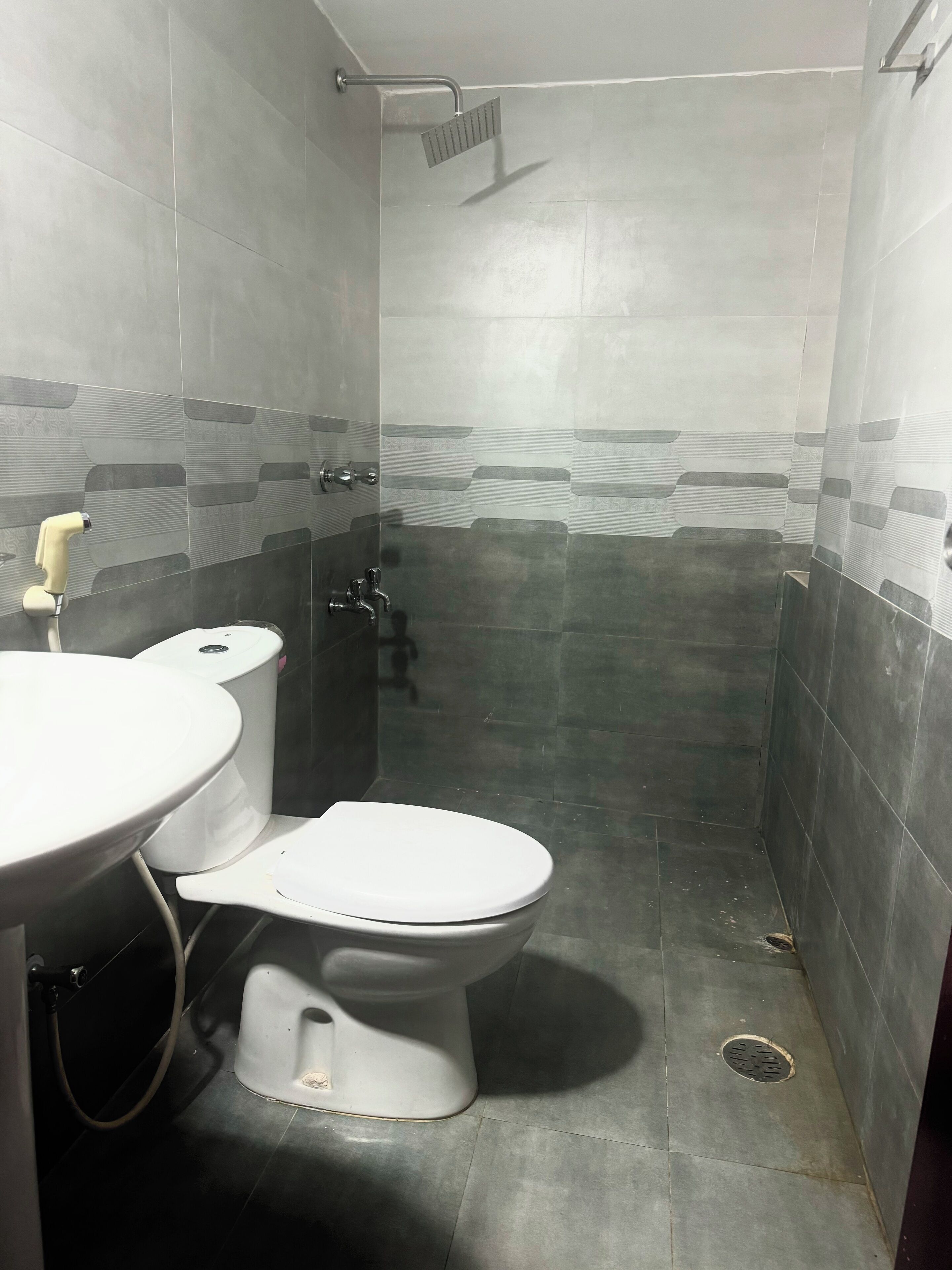A small, tiled bathroom with a toilet, sink, and shower.