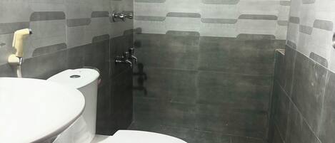 A small, tiled bathroom with a toilet, sink, and shower.